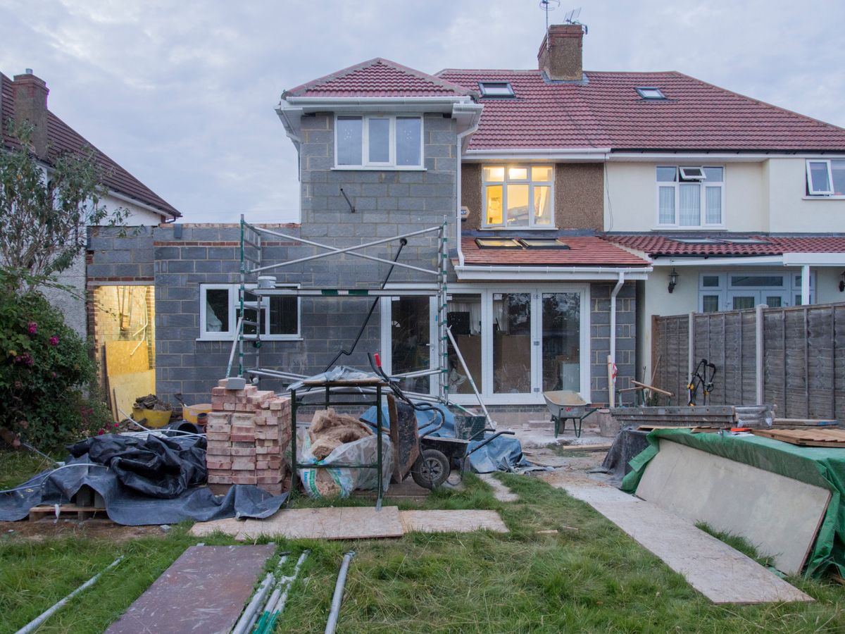 House renovation in progress with scaffolding, masonry and an unfinished addition